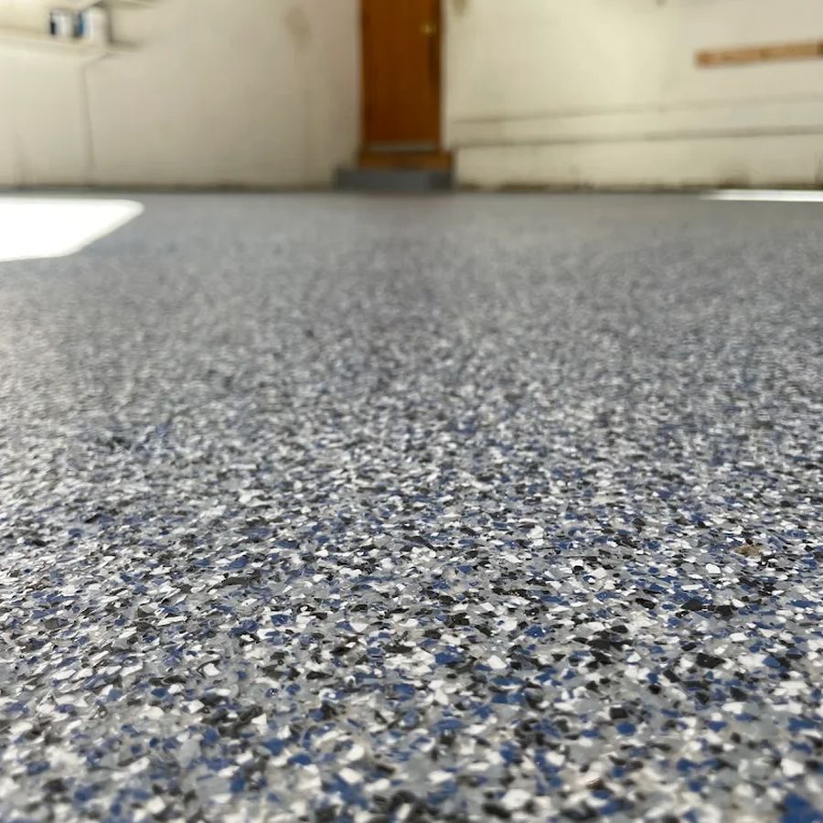 Close-up of a blue, gray and white flake epoxy garage floor with a glossy top coat