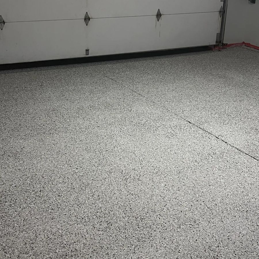 Full-width flake epoxy garage floor coating in front of a white garage door
