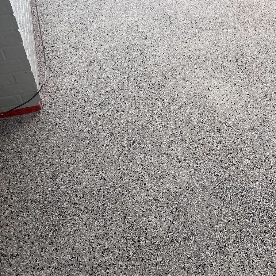 Seamless gray flake epoxy garage floor finished cleanly along the wall
