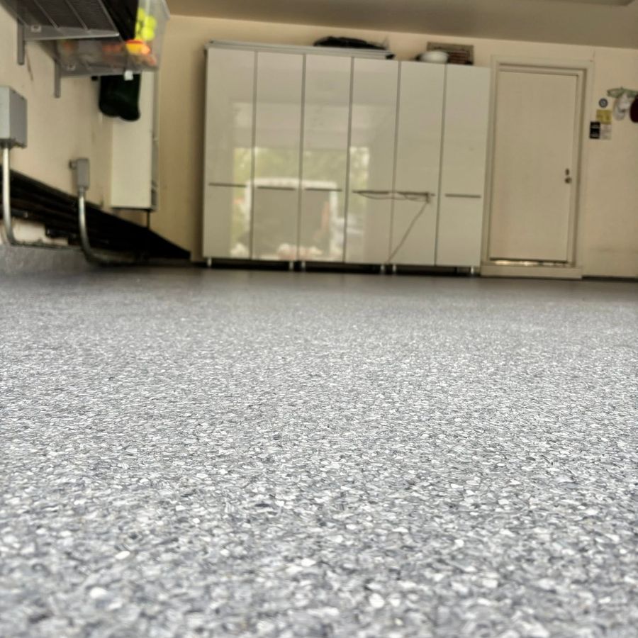 Low-angle view of a gray flake epoxy garage floor with white storage cabinets